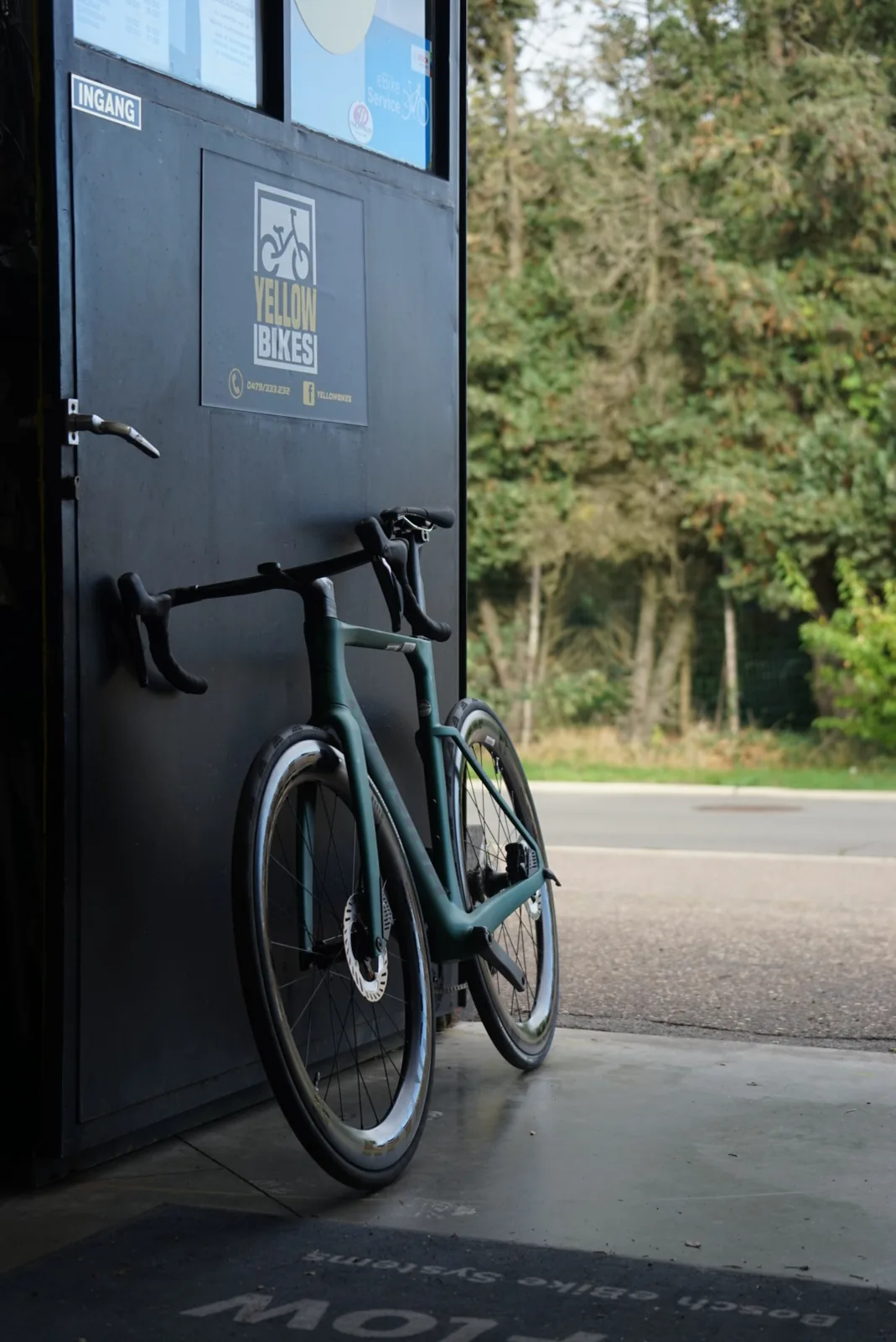 Groene koersfiets aan de ingang van Yellow Bikes in Schoonbeek